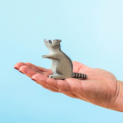 Hand holding Wooden Sitting Raccoon for size reference
