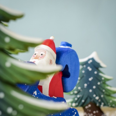 Close-up of Santa with Snowy Fir Trees in background.