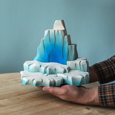 Adult hands holding the large wooden iceberg toy to demonstrate its substantial 19cm height and 25cm width.