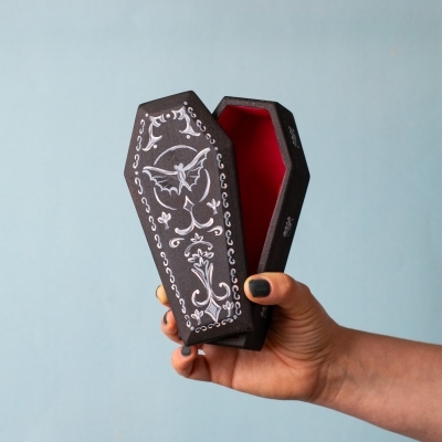Hand holding wooden Dracula coffin toy with painted bat design on lid