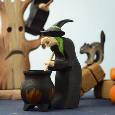 Brewing witch figurine in a Halloween-themed scene with a cauldron and other wooden figures.