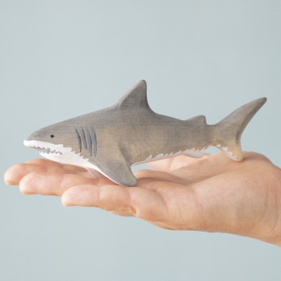 Wooden shark toy resting in a child’s palm – size comparison