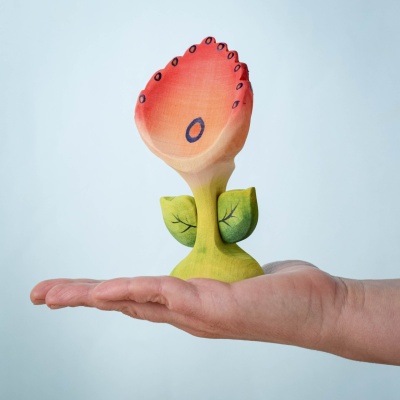 Close-up of Spring Flower - Perla wooden toy with red and orange petals, held in a hand, showcasing its eco-friendly, handcrafted design.