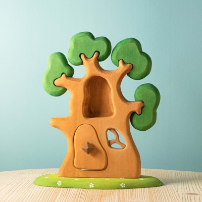 Image of the "The Ancient Oak" treehouse on a natural wooden table, sunlight streaming through its leaves.