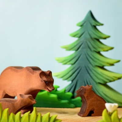 Wooden bear cub with a bear family and trees background