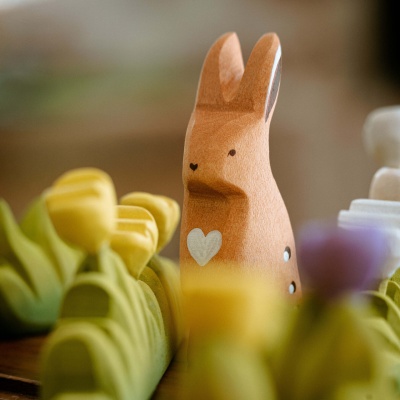 A wooden rabbit toy from BumbuToys, poised in a careful and observant posture.