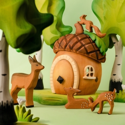 Side view of the wooden acorn house toy showing the green base and two small windows