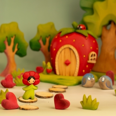 BumbuToys scene featuring the Flower Child Poppy on a path with wooden hearts leading to the Strawberry House.