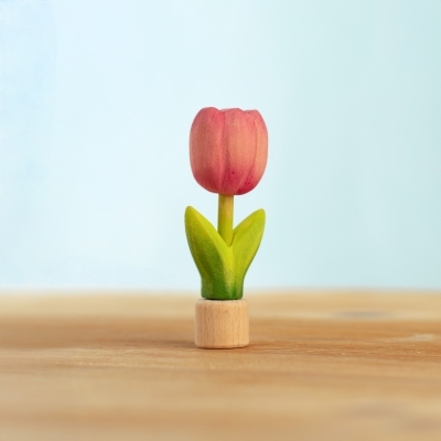 Single pink wooden tulip toy standing upright on a light wood tabletop
