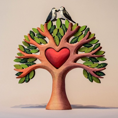 A decorative wooden sculpture of a tree with a heart, with two small birds perched on top.
