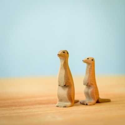 Handcrafted wooden meerkat figurines on a wooden surface