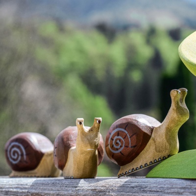 Trio of wooden snail toys with scenic background