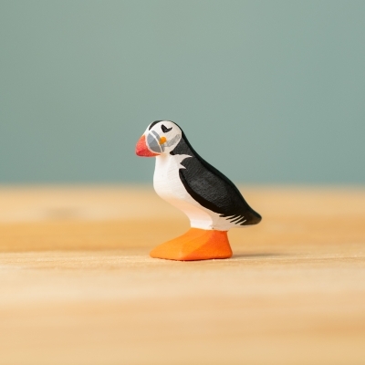 Handcrafted wooden puffin toy with colorful painted beak and natural wood belly, side profile.