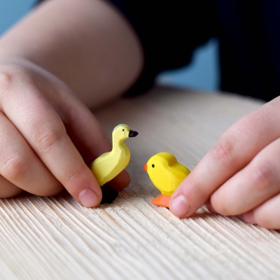 A child using the BumbuToys Wooden Chicks to create a pretend nest scene.
