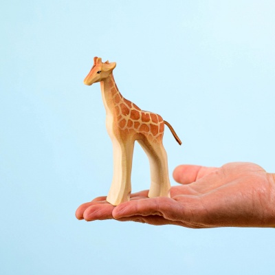 Hand holding the adorable organic wooden giraffe calf toy.