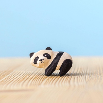 Side view of a wooden panda bear cub figurine with detailed painting