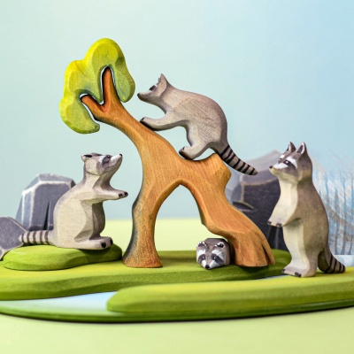 Woodland play scene with wooden raccoon standing curiously