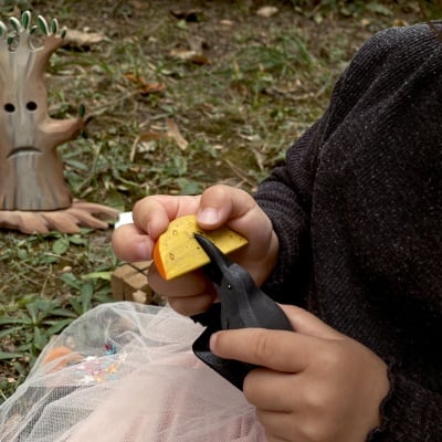 A child using the raven and cheese in pretend play, acting out a story or creating a scene.