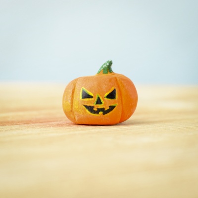 Small wooden Halloween pumpkin with a jack-o'-lantern face.
