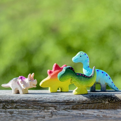 Wooden Triceratops Baby with other dinosaur toys in natural background