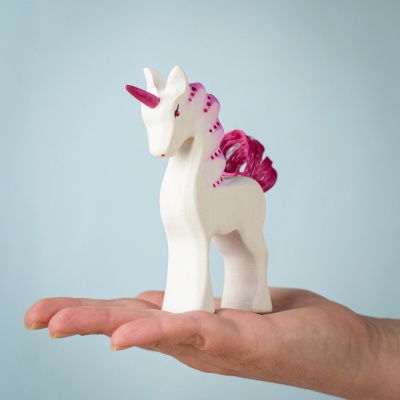 A child holding the Baby Unicorn Pastel in their palm, showcasing its size.