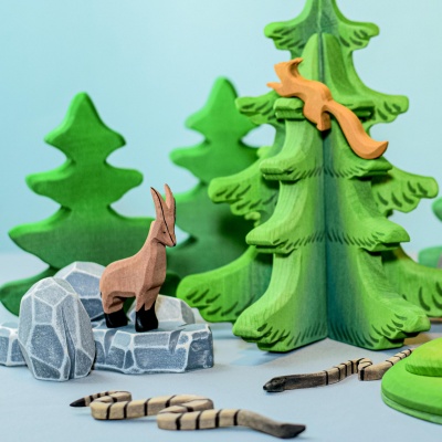 The wooden tree incorporated into a sensory bin filled with cotton balls, pine cones, and other winter-themed materials.