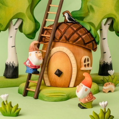 Close up of a wooden acorn house with white bunnies and a toy carrot