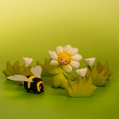 Wooden bumblebee figure flying next to the Flower Child Daisy toy, perfect for pollination play.