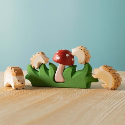 Image of the Hedgehogs and Mushroom Set on a natural wooden table with sunlight dappling the pieces.