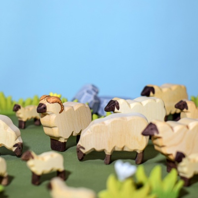 The lamb figurine integrated into a pretend play scenario with a wooden barn or farmhouse.