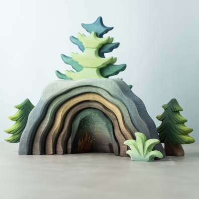Dragon’s Cave in a fantasy forest scene with pine trees and greenery.