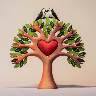A handcrafted wooden tree decoration with a heart-shaped center, featuring two small birds perched on top.