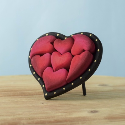 Handcrafted Red Hearts Puzzle featuring a black wooden heart frame with seven red heart pieces.