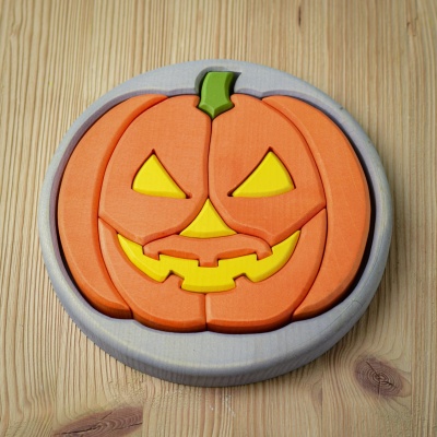 Handcrafted wooden round Halloween puzzle with a grey base and pumpkin design, fully assembled.