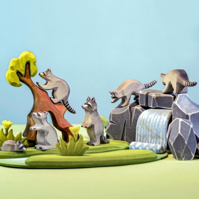 Raccoon family and curious raccoon by a miniature tree