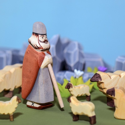 The shepherd figurine incorporated into a miniature folklore scene with other wooden characters and animals.