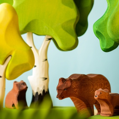 Wooden bear cub with bear family among colorful trees