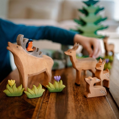 Wooden fawn toy by Bumbu Toys, lying down in a restful state.