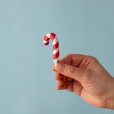 Wooden candy cane held in hand for size reference.