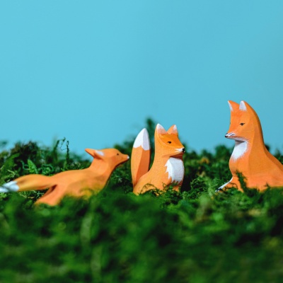 The fox figurine sitting peacefully beneath a miniature wooden tree.