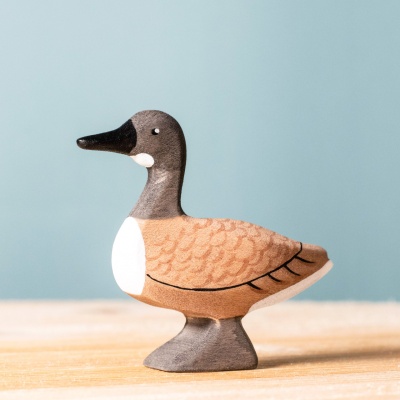 Image of the BumbuToys Wild Goose standing proudly on a natural wooden surface with sunlight streaming through.