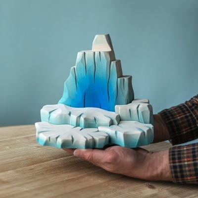 Adult hands holding the large 25cm wooden iceberg to demonstrate its substantial size and weight.