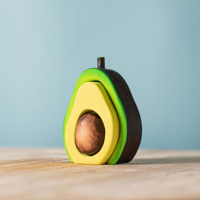 Realistic wooden avocado with pit by BumbuToys, alongside grapes and strawberry.