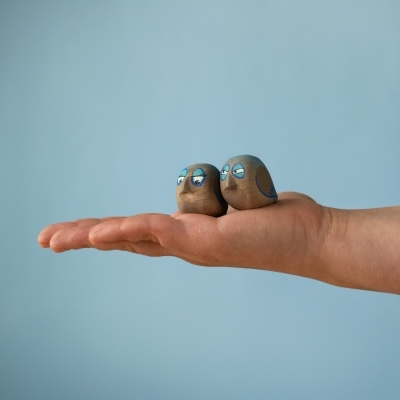Adult hand holding two miniature wooden bird toys to demonstrate the small 3cm size.