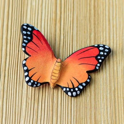 Wooden butterfly toy lying flat on a wooden surface