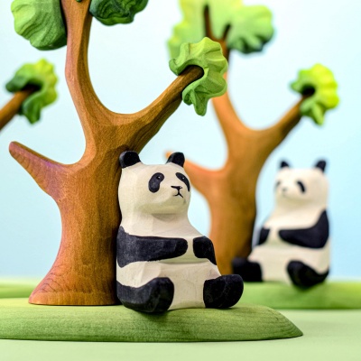 Close-up of wooden panda bear sitting beside a wooden tree