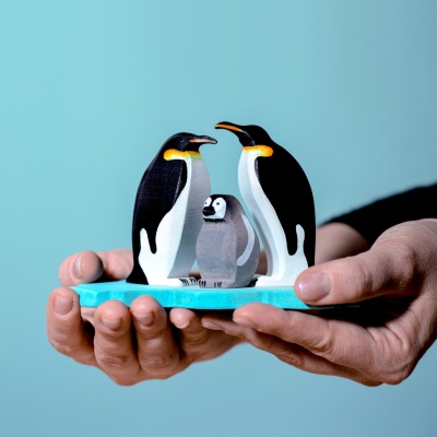 A gathering of hand-painted penguins from BumbuToys, set against a crafted wooden ice floe.