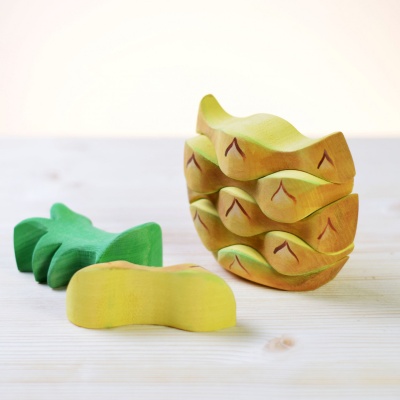 The Pineapple stacking toy from BumbuToys, deconstructed to show each detailed segment and leafy crown.