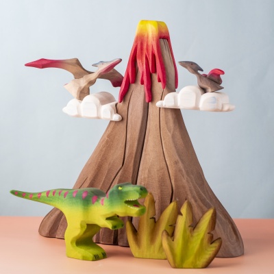 Pteranodon figurines flying around a wooden volcano with other dinosaurs.