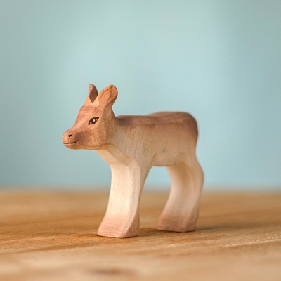Handmade wooden Reindeer Calf figure standing with an alert expression against a solid blue background.